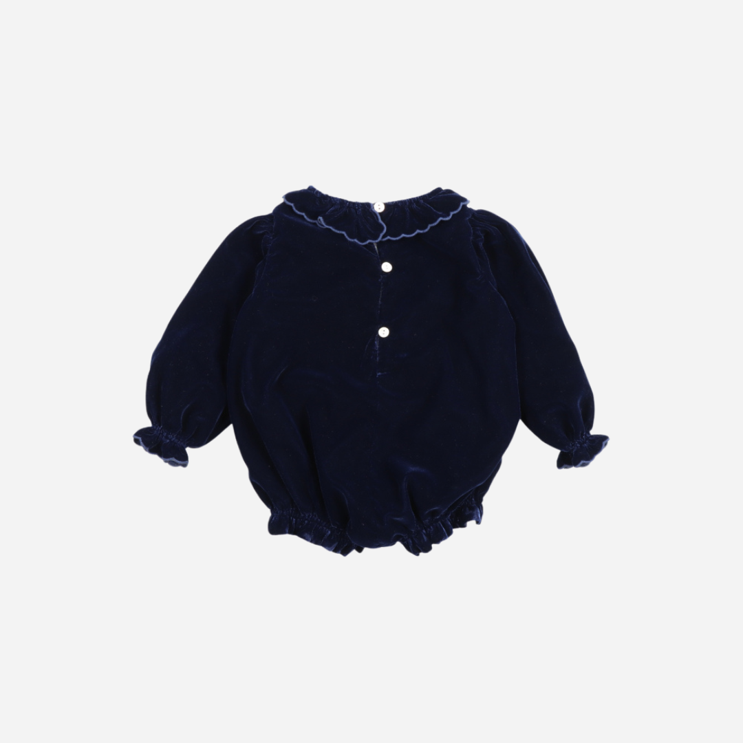 Sold at Bombon shop, this baby girl romper by The New Society is crafted in deep navy velvet with gathered hems, ruffled collar and cuffs, and floral embroidery on the chest—perfect for a festive or special occasion look. back