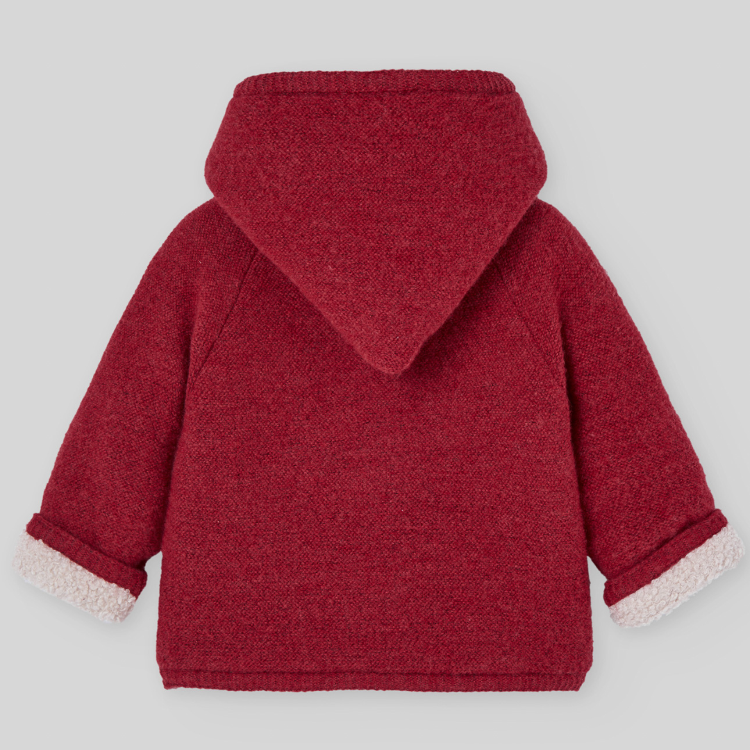 Sold at Bombon shop, designed by Paz Rodriguez, red hooded winter coat with faux-shearling lining and wooden buttons from the Acebo collection