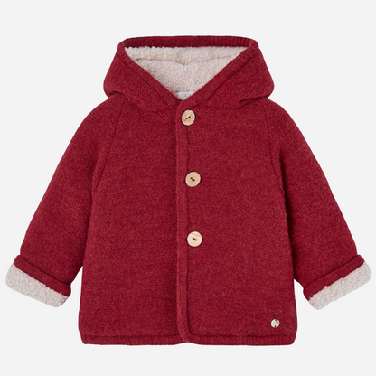 Sold at Bombon shop, designed by Paz Rodriguez, red hooded winter coat with faux-shearling lining and wooden buttons from the Acebo collection
