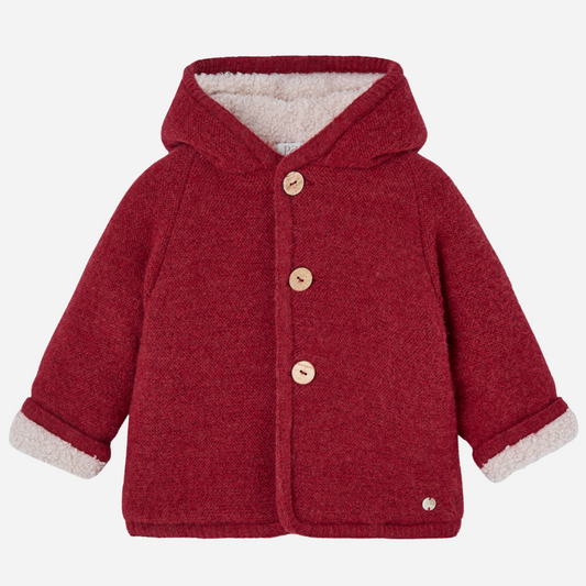 Sold at Bombon shop, designed by Paz Rodriguez, red hooded winter coat with faux-shearling lining and wooden buttons from the Acebo collection