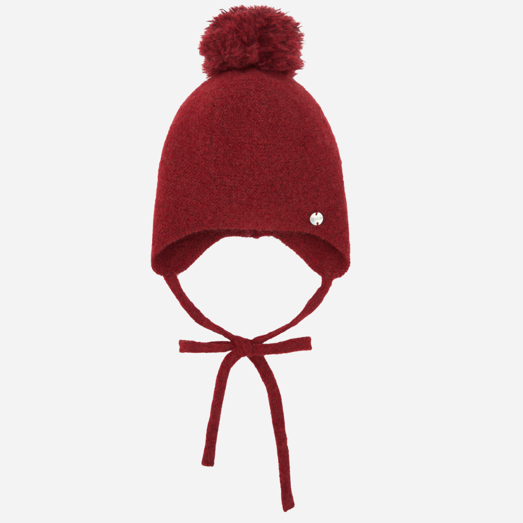 Sold at Bombon shop, designed by Paz Rodriguez, red wool baby bonnet with pom-pom and ties, part of the Acebo collection.
