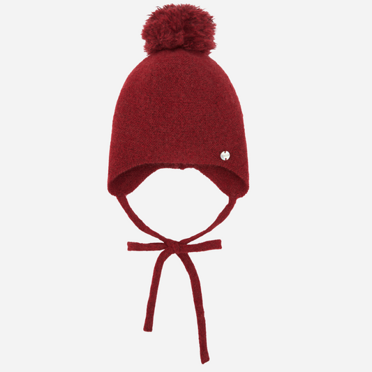 Sold at Bombon shop, designed by Paz Rodriguez, red wool baby bonnet with pom-pom and ties, part of the Acebo collection.