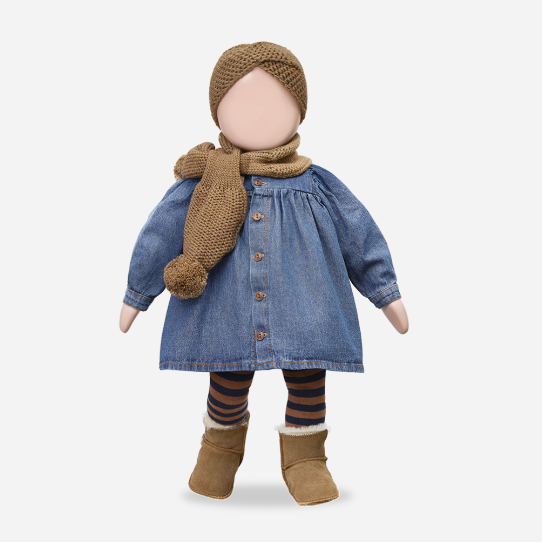 Sold at Bombon shop, designed by 1+ in the family — soft denim baby dress with long sleeves, wooden buttons, and gathered waist. manequin