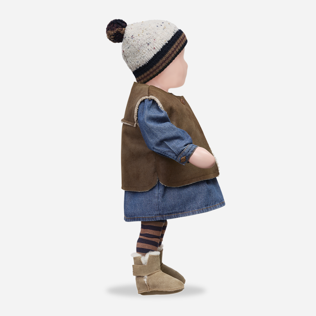 Sold at Bombon shop, designed by 1+ in the family — soft denim baby dress with long sleeves, wooden buttons, and gathered waist. manequin