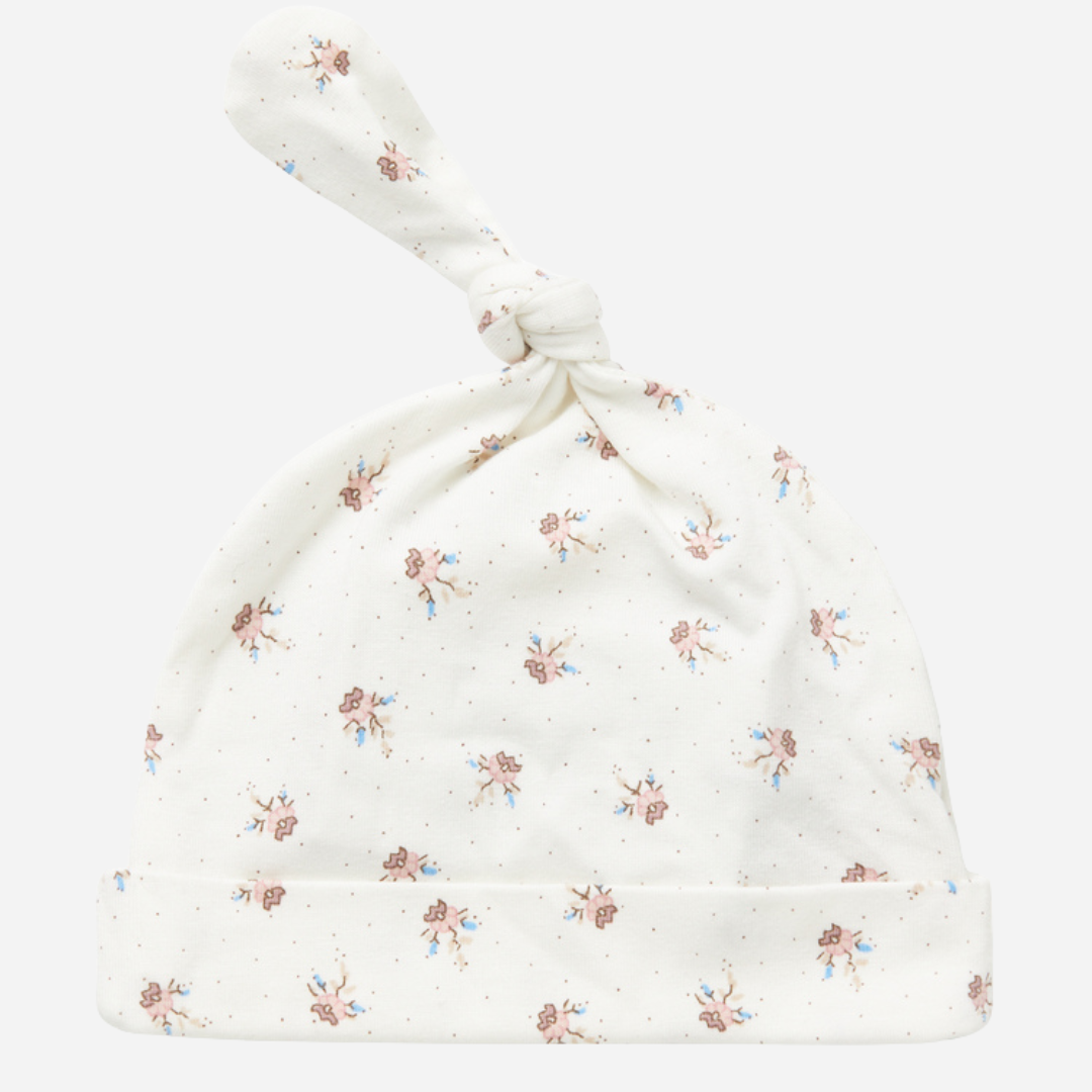 Sold at Bombon shop, designed by MarMar Copenhagen — white organic cotton baby hat with floral print and top knot, part of a matching set.