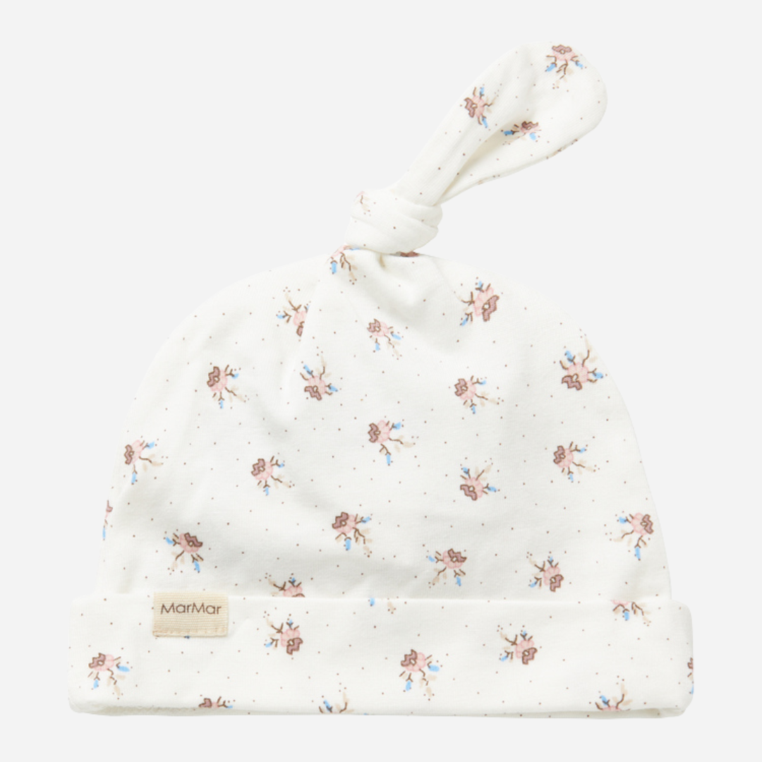 Sold at Bombon shop, designed by MarMar Copenhagen — white organic cotton baby hat with floral print and top knot, part of a matching set.