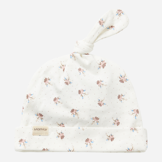 Sold at Bombon shop, designed by MarMar Copenhagen — white organic cotton baby hat with floral print and top knot, part of a matching set.