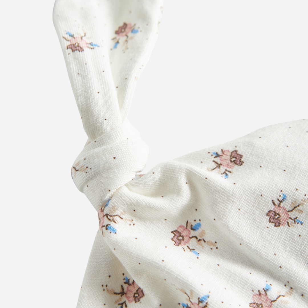 Sold at Bombon shop, designed by MarMar Copenhagen — white organic cotton baby hat with floral print and top knot, part of a matching set.