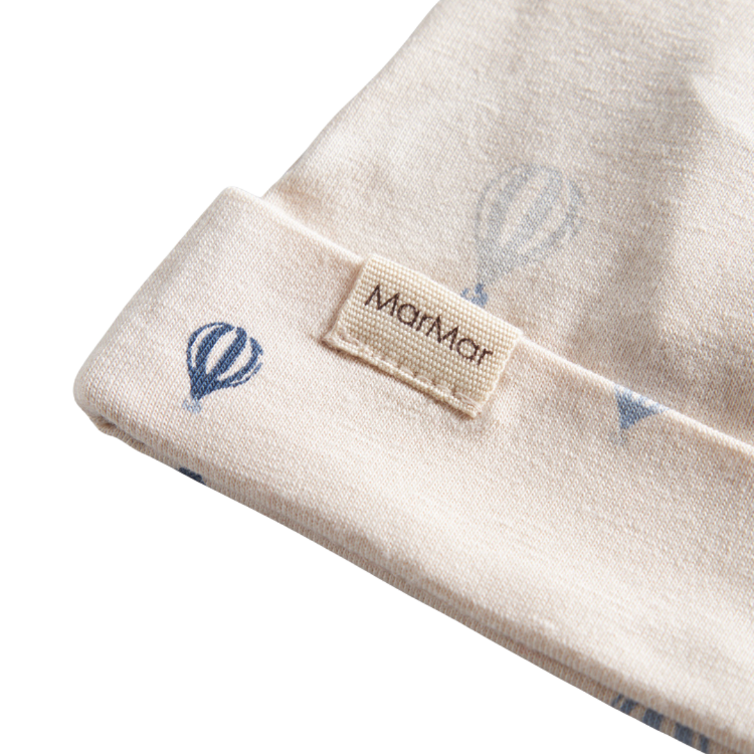 Sold at Bombon shop, designed by MarMar Copenhagen. Cream baby blanket with blue air balloon print, pairs perfectly with the matching air balloon hat and wrap footie.