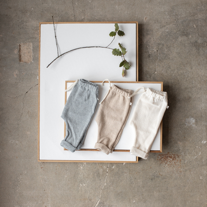 Sold at Bombon shop, designed by 1+ in the family — baby pants in pale blue nuvola knit with rolled hems and natural drawstring waist. lifestyle