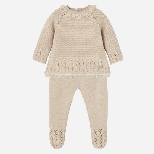 Sold at Bombon shop, designed by Paz Rodriguez. Baby girl beige knit two-piece set with lace trim, pointelle knit, ruffled collar, and footed pants.