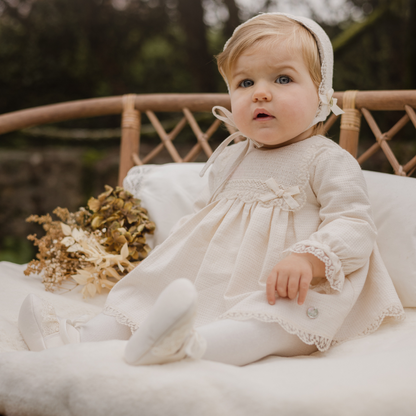 Sold at Bombon shop, designed by Paz Rodriguez, beige baby dress with lace trim, smocked bodice, and matching bloomers.