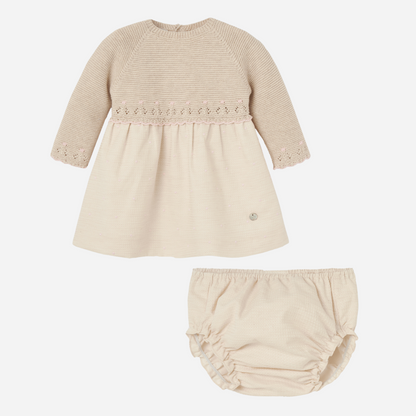Sold at Bombon shop, designed by Paz Rodriguez. Baby girl knitted dress in beige with pink embroidered detail, long sleeves, and matching bloomers.