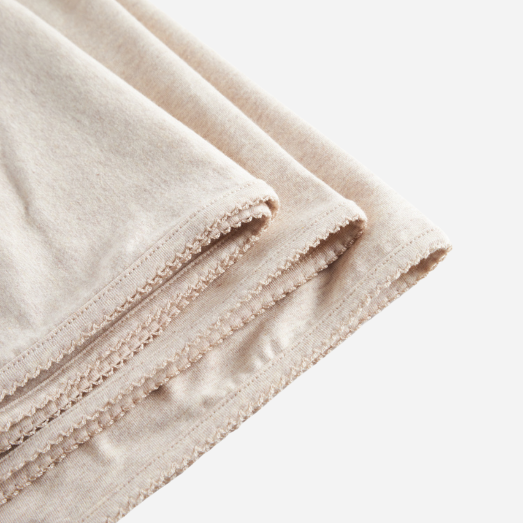 Sold at Bombon shop, designed by MarMar Copenhagen — beige organic cotton baby blanket with scalloped edge.
