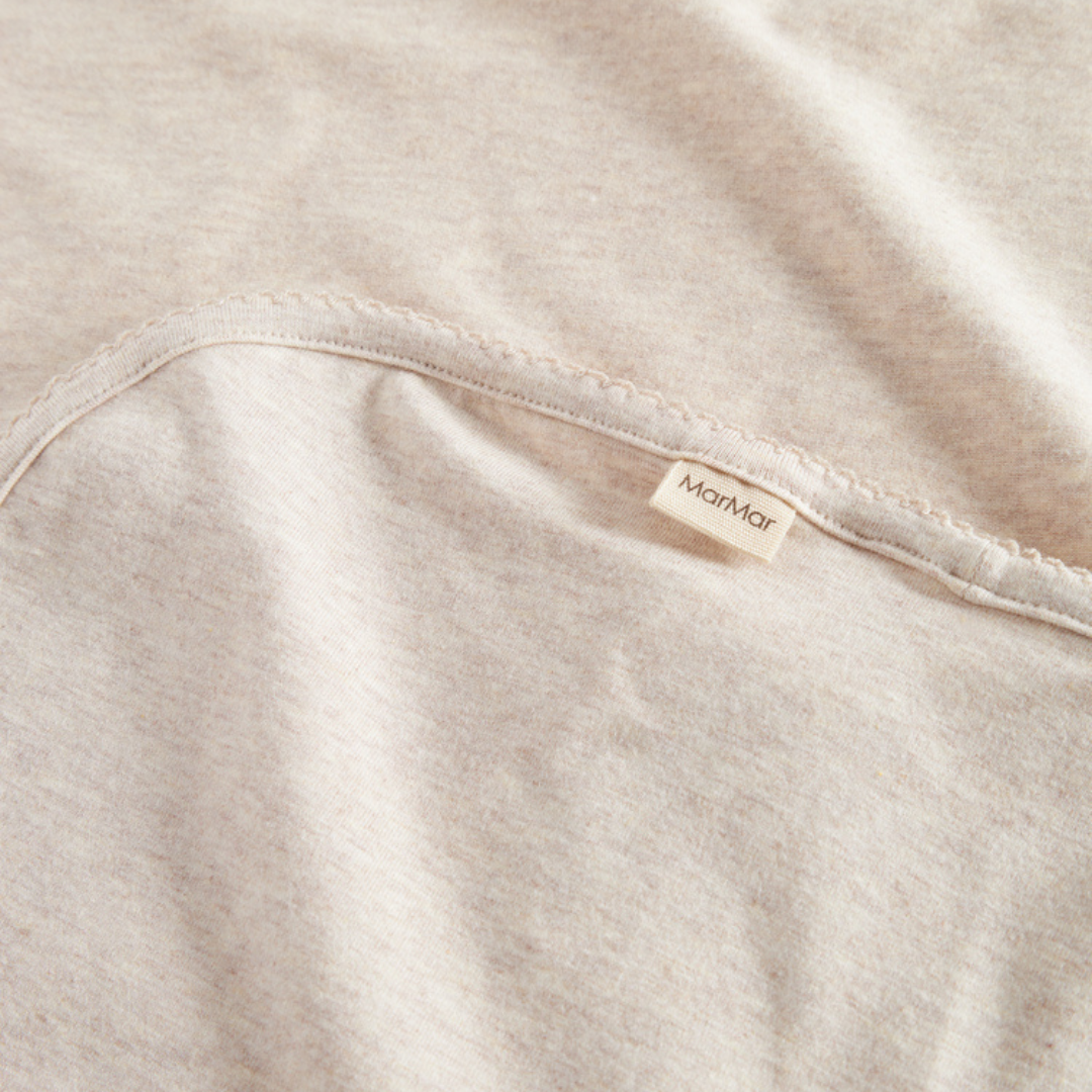 Sold at Bombon shop, designed by MarMar Copenhagen — beige organic cotton baby blanket with scalloped edge.