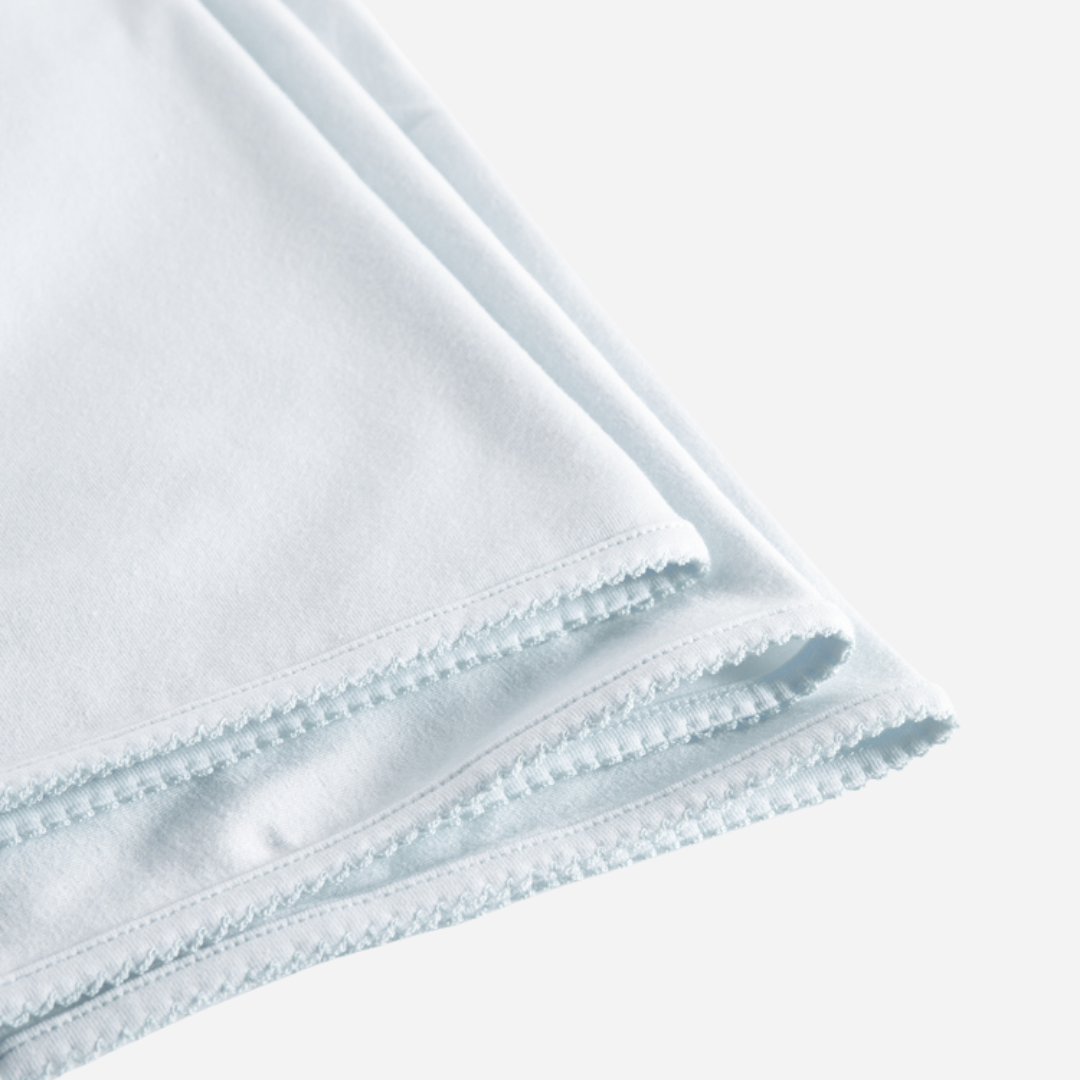 Sold at Bombon shop, designed by MarMar Copenhagen — powder blue organic cotton baby blanket with scalloped edge.