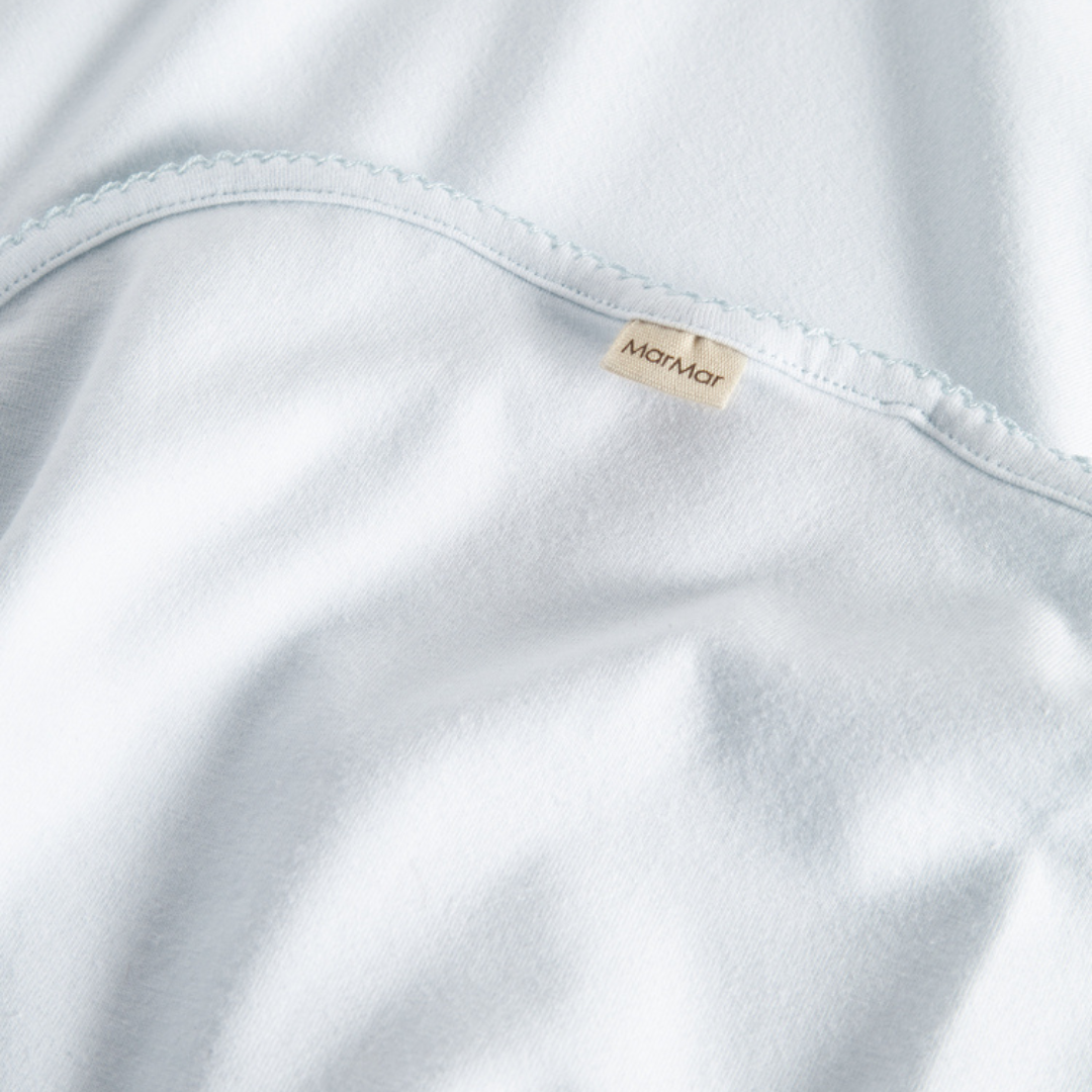Sold at Bombon shop, designed by MarMar Copenhagen — powder blue organic cotton baby blanket with scalloped edge.