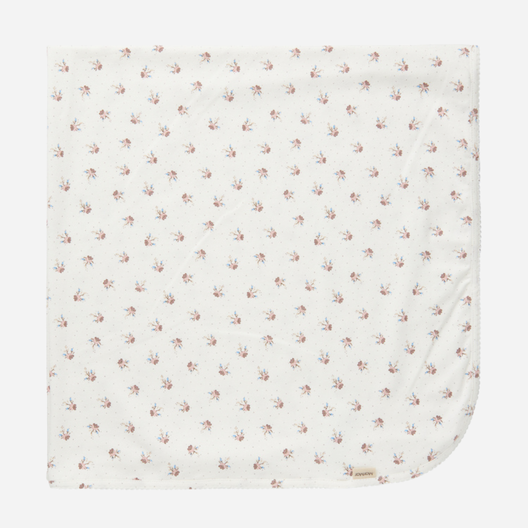 Sold at Bombon shop, designed by MarMar Copenhagen — white organic cotton baby blanket with floral print, part of a matching set.