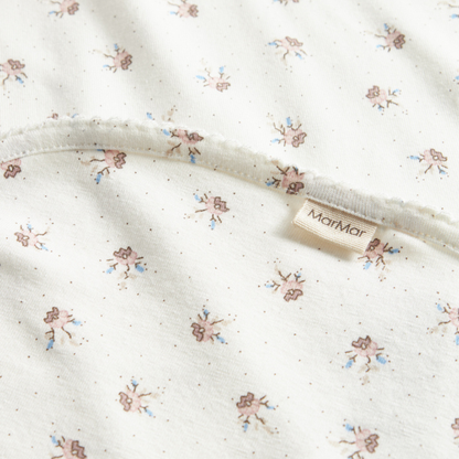 Sold at Bombon shop, designed by MarMar Copenhagen — white organic cotton baby blanket with floral print, part of a matching set.