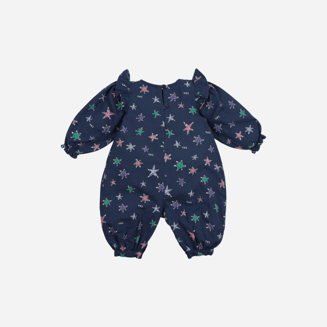 Sold at Bombon shop, this baby girl romper by The New Society features a navy background with a colorful star print, puffed long sleeves, ruffle shoulder details, and gathered cuffs for a whimsical and comfortable all-in-one outfit. back