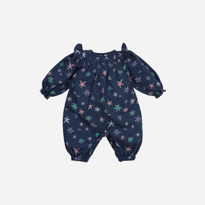 Sold at Bombon shop, this baby girl romper by The New Society features a navy background with a colorful star print, puffed long sleeves, ruffle shoulder details, and gathered cuffs for a whimsical and comfortable all-in-one outfit. front