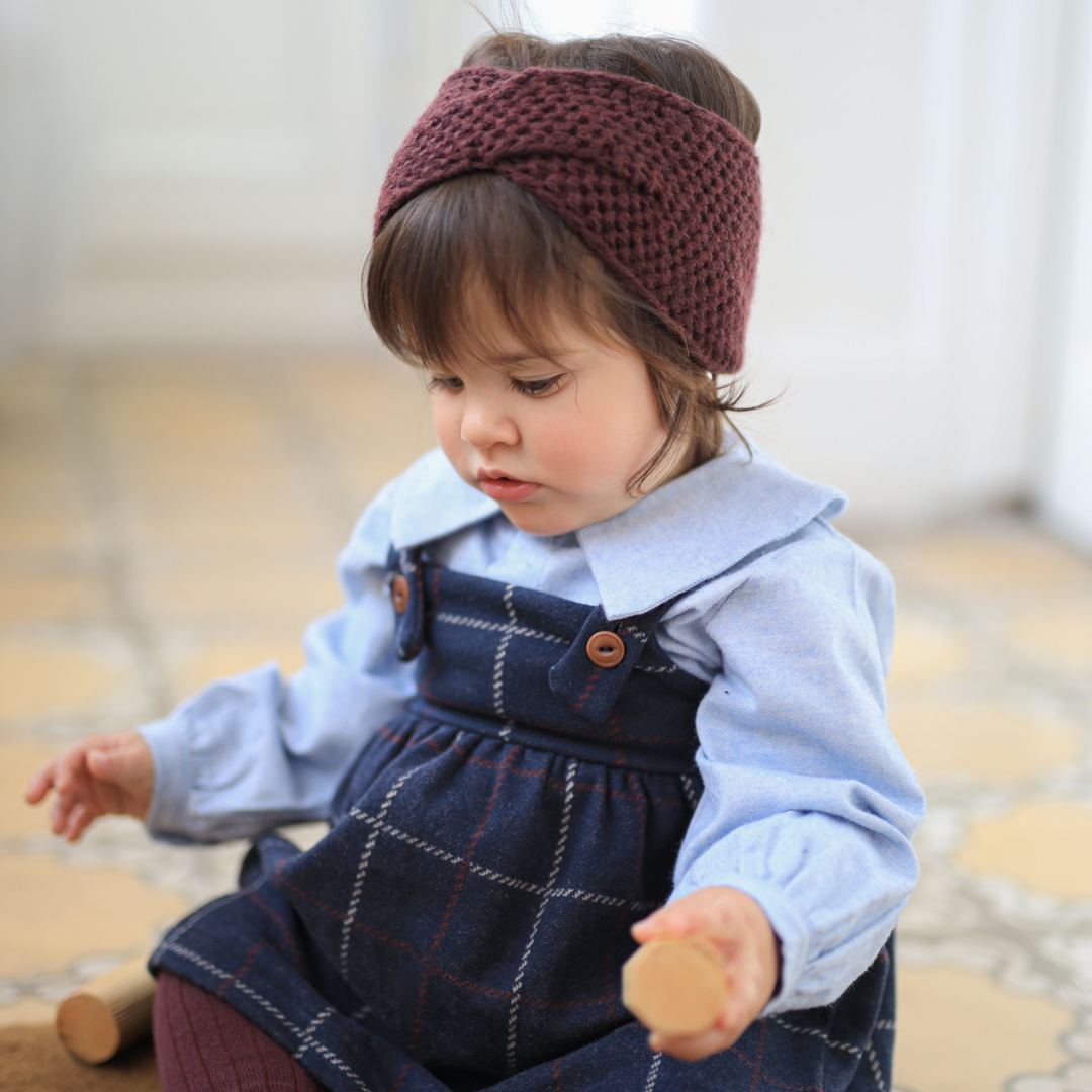 Sold at Bombon shop, designed by 1+ in the family — deep aubergine knit bandana with a twist front, crafted for warmth and comfort. model