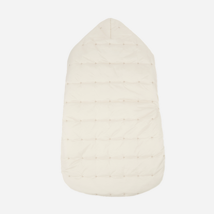 Sold at Bombon shop, designed by 1+ in the family — cream-colored quilted baby nest with hood and side button closure, crafted for warmth and comfort. back