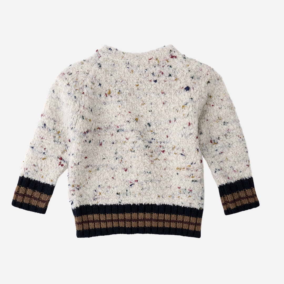 Sold at Bombon shop, designed by 1+ in the family — speckled knit baby sweater with contrast ribbed cuffs and buttoned shoulder, in cream with navy and brown accents. back