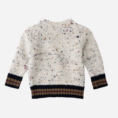 Sold at Bombon shop, designed by 1+ in the family — speckled knit baby sweater with contrast ribbed cuffs and buttoned shoulder, in cream with navy and brown accents. back