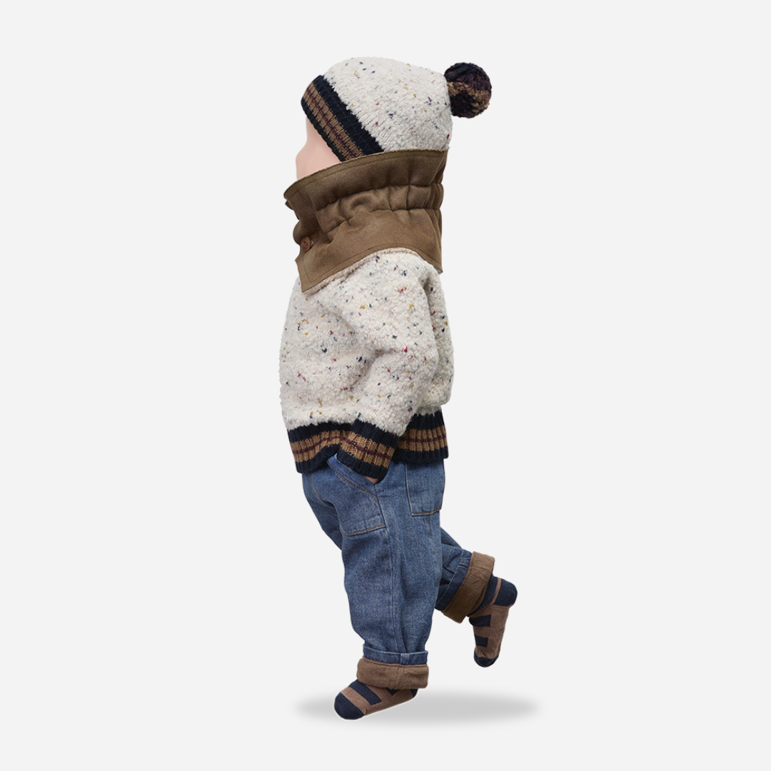 Sold at Bombon shop, designed by 1+ in the family — speckled knit baby sweater with contrast ribbed cuffs and buttoned shoulder, in cream with navy and brown accents. manequin