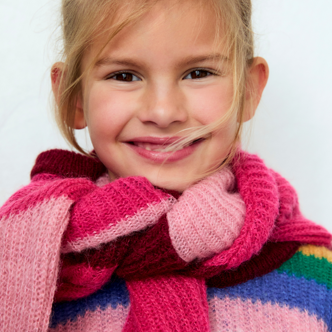 Sold at Bombon Shop, this girls’ sweater by The New Society features bold multicolor stripes in a soft ribbed knit, blending playful tones of pink, burgundy, green, and blue with a cozy crewneck silhouette. model