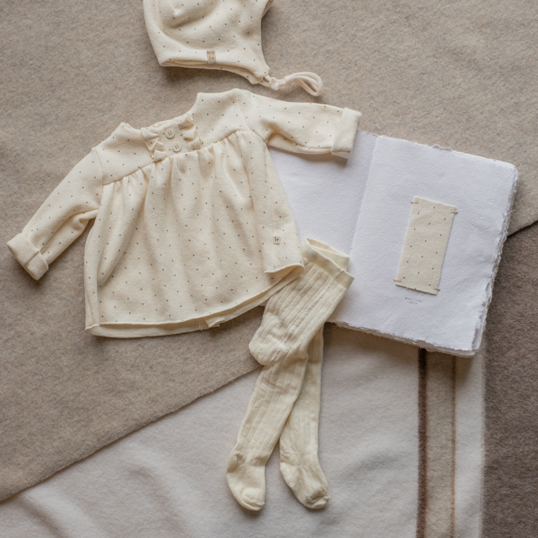 Sold at Bombon shop, designed by 1+ in the family — ecru ribbed baby tights with enclosed feet, photographed flat on white background. lifestyle