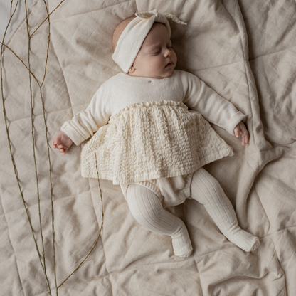 Sold at Bombon shop, designed by 1+ in the family — ecru ribbed baby tights with enclosed feet, photographed flat on white background. model