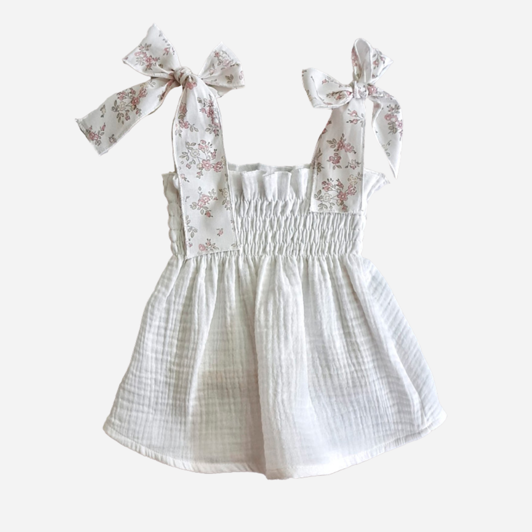 Sold at Bombon shop, designed by Paloma de la O brand, this two piece set for baby girls in white with light pink flower details is ideal for spring and summer.  Top detail