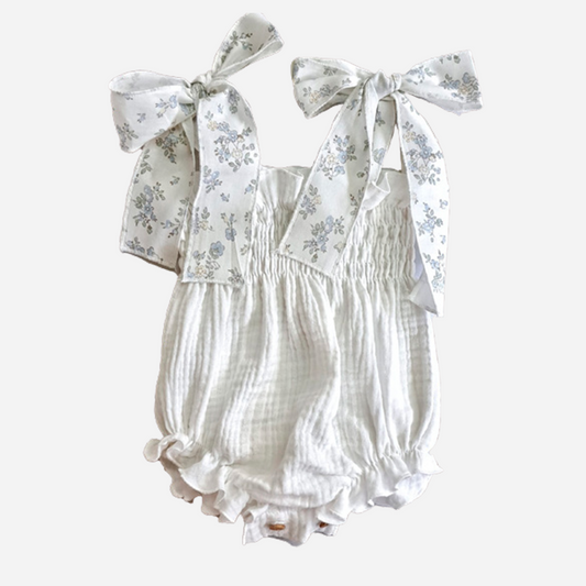 Sold at Bombon shop, designed by Paloma de la O brand, this romper for baby girls in white with light blue flower details is ideal for spring and summer