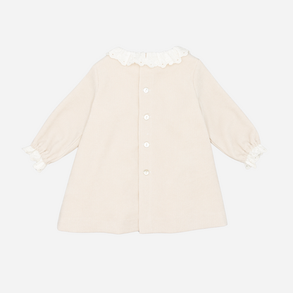 Sold at Bombon shop, designed by Fina Ejerique, a beige corduroy baby dress with smocked bodice, white ruffle collar, and long sleeves. back