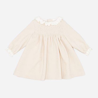 Sold at Bombon shop, designed by Fina Ejerique, a beige corduroy baby dress with smocked bodice, white ruffle collar, and long sleeves. front