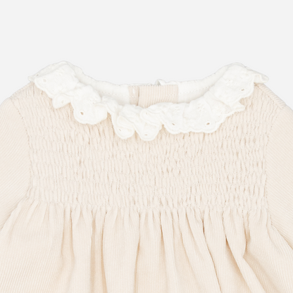 Sold at Bombon shop, designed by Fina Ejerique, a beige corduroy baby dress with smocked bodice, white ruffle collar, and long sleeves. zoom