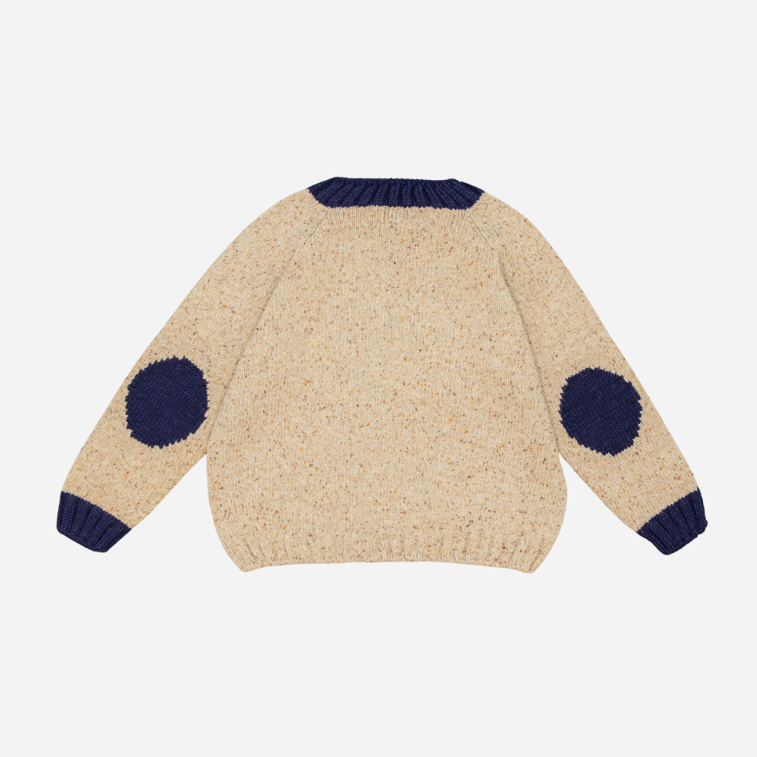 Sold at Bombon shop, designed by Fina Ejerique, a beige knit baby sweater with navy ribbed collar and cuffs, styled to pair with the multicolor checkered shirt. back