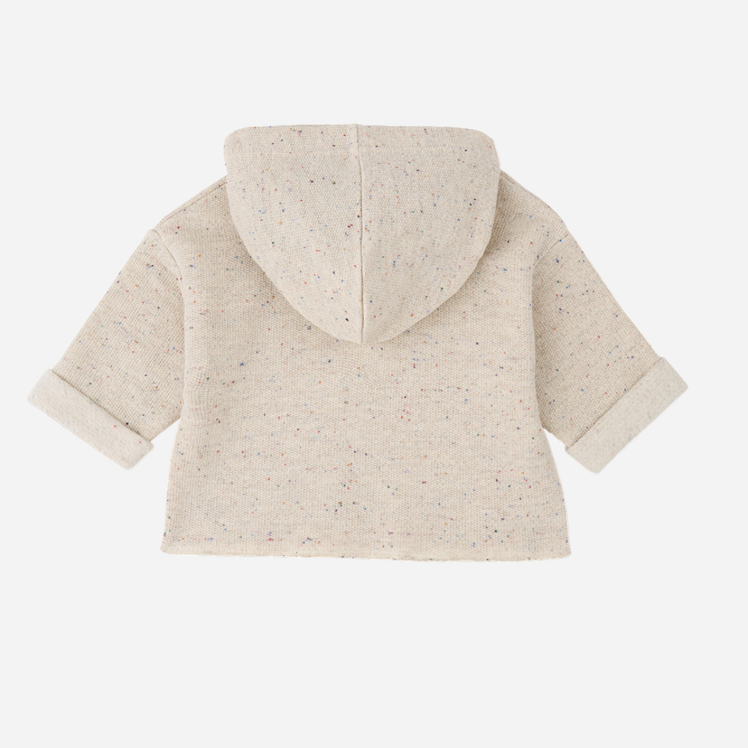 Sold at Bombon shop, designed by 1+ in the family — oatmeal-colored speckled baby hoodie with wooden button and rolled cuffs, photographed flat on white background. back