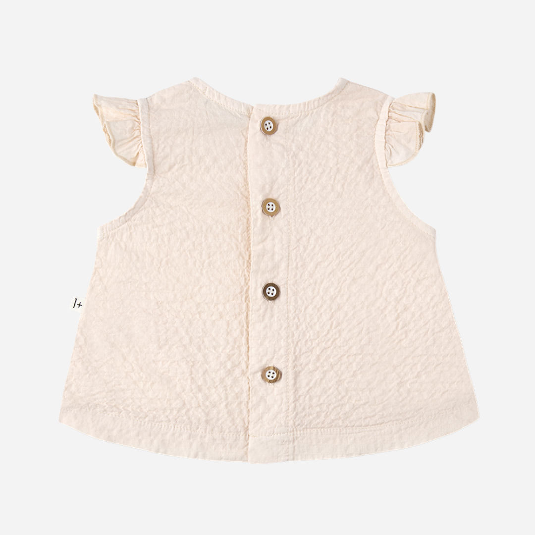 Sold at Bombon Shop, designed by 1+ in the family, blossom pink baby blouse with flutter sleeves and matching bloomers in textured cotton fabric.