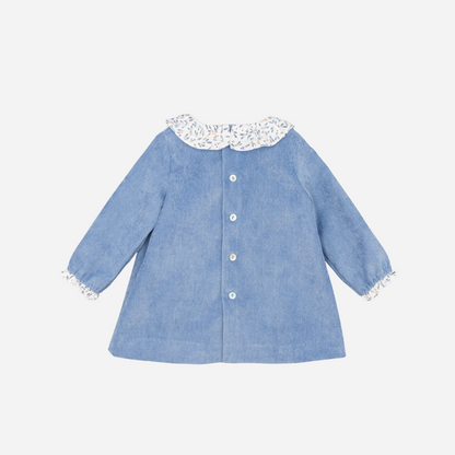 Sold at Bombon shop, designed by Fina Ejerique, a sky-blue corduroy baby dress with floral ruffle collar, bow detail, and long sleeves. back
