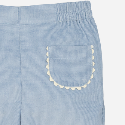 Sold at Bombon shop, designed by Fina Ejerique, a pair of sky-blue corduroy baby pants with scallop-trimmed back pockets and elastic waistband. zoom