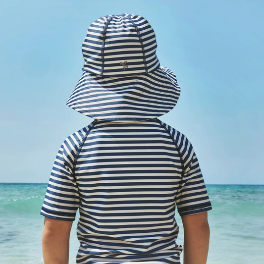 Sold at Bombon Shop, designed by Wheat, blue stripe UV sun hat in recycled fabric with soft brim and navy striped pattern.