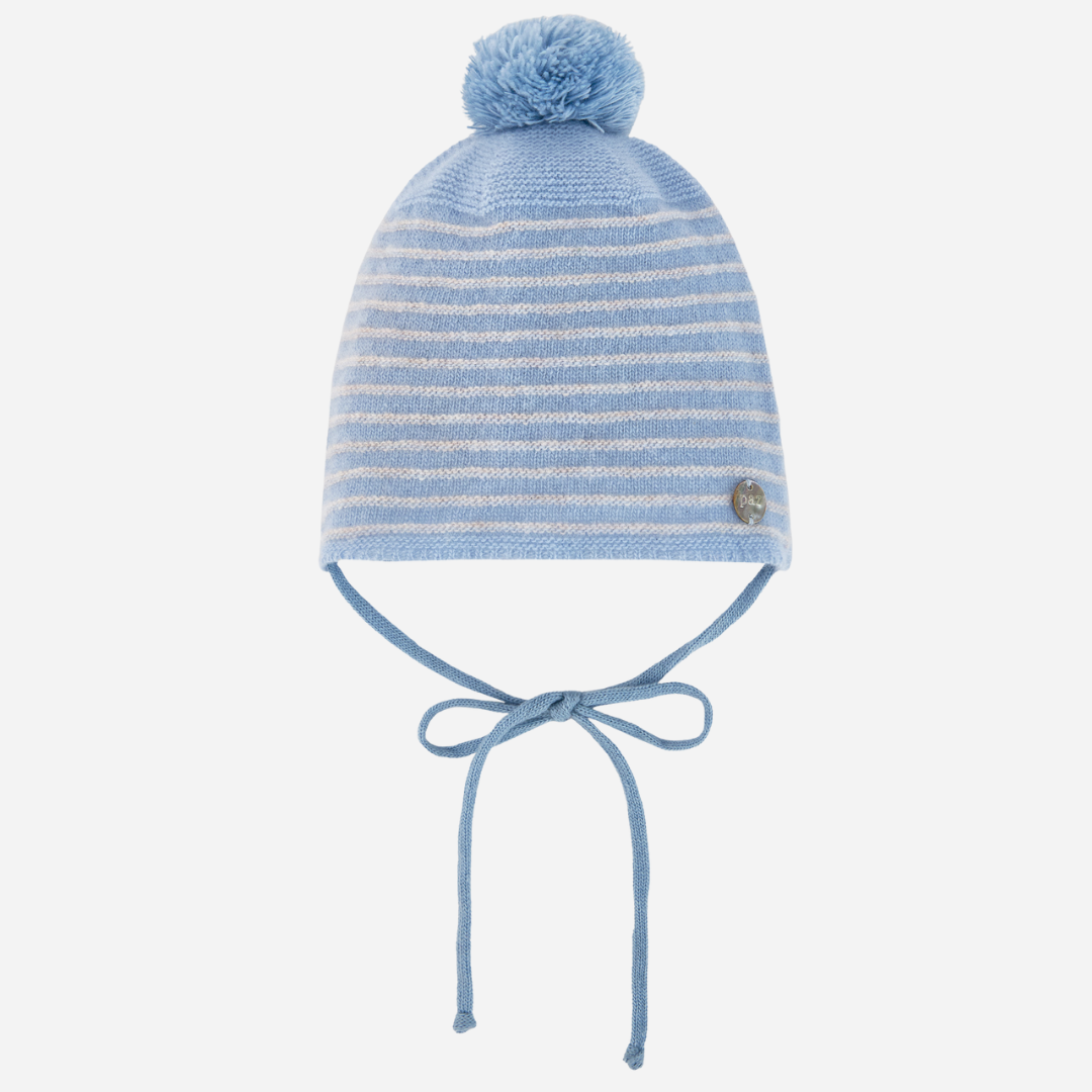 Sold at Bombon shop, designed by Paz Rodriguez. Baby cashmere hat in pale blue with pompom and ties, shown from front view.