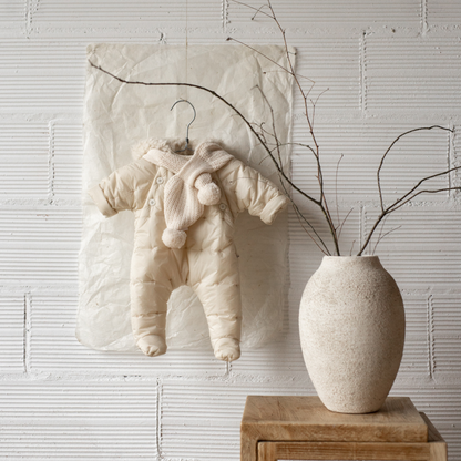 Sold at Bombon shop, designed by 1+ in the family — ecru padded baby snowsuit with star quilting, sherpa-lined hood, and front button closures, displayed flat on a white background. lifestyle