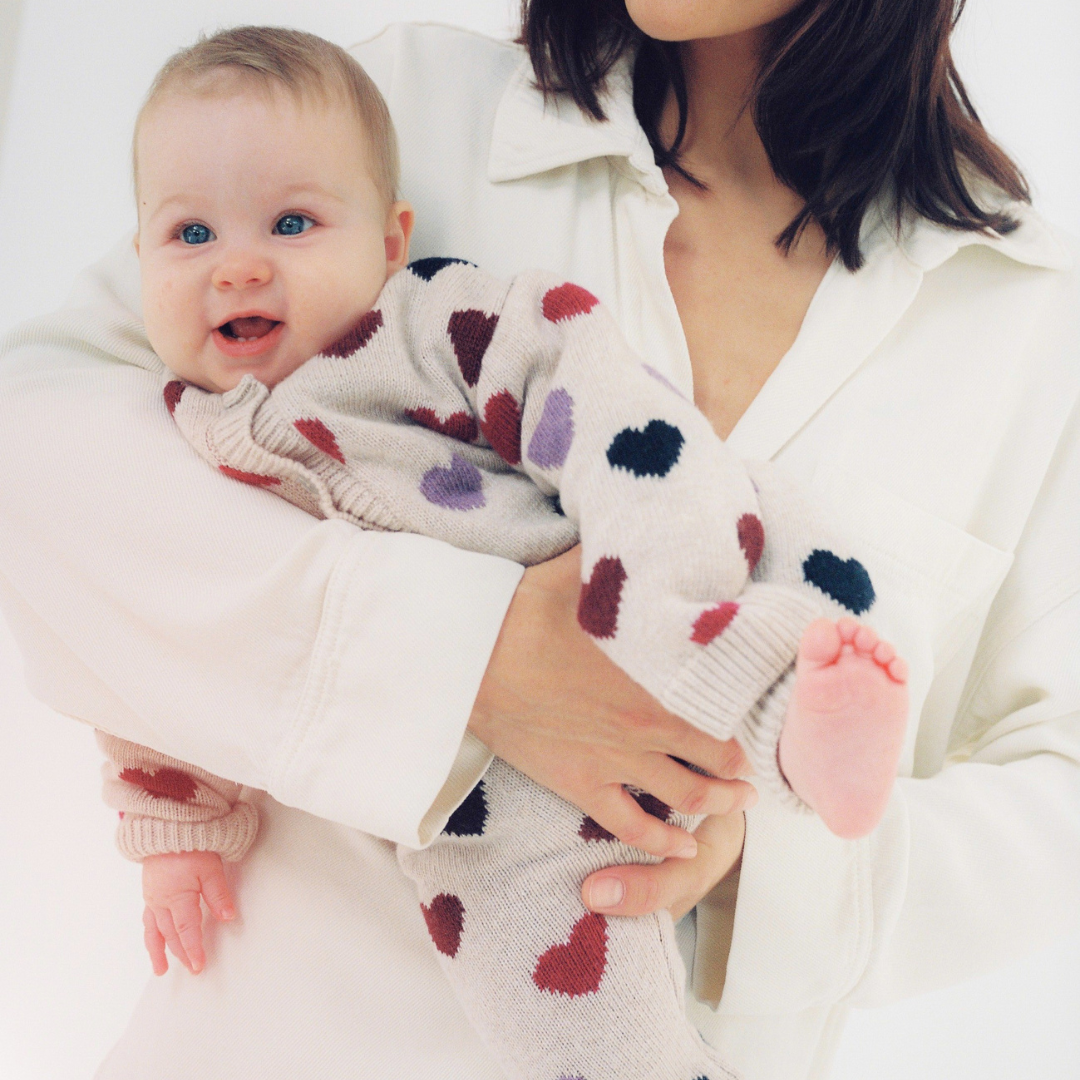 Sold at Bombon Shop, these baby girl knit pants by The New Society come in a soft beige hue with an allover multicolor heart pattern and ribbed trims. model