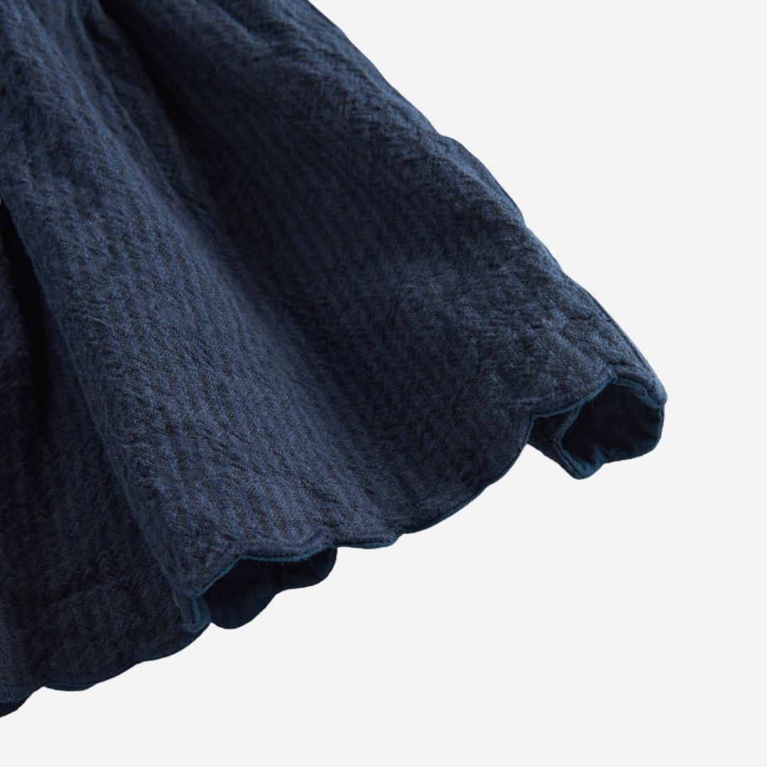 Sold at Bombon shop, designed by MarMar Copenhagen — navy 100% cotton textured pinafore dress with scalloped edges, pairs perfectly with the cream blouse.