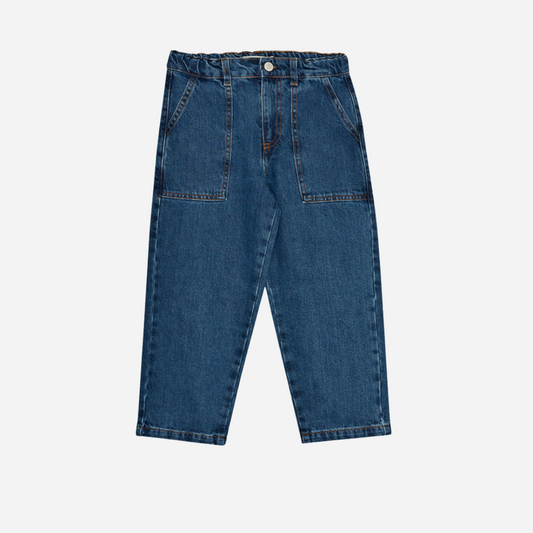 Sold at Bombon shop, these kids' denim pants by The New Society feature a relaxed, baggy fit with front patch pockets, an elastic waistband at the back, and a button closure—offering comfort and style for everyday wear. front