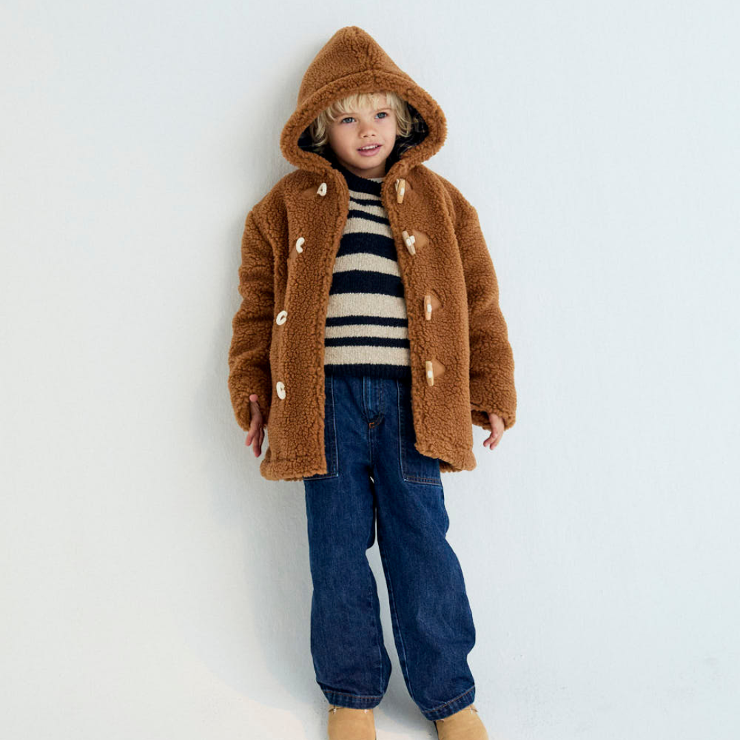 Sold at Bombon shop, these kids' denim pants by The New Society feature a relaxed, baggy fit with front patch pockets, an elastic waistband at the back, and a button closure—offering comfort and style for everyday wear. model